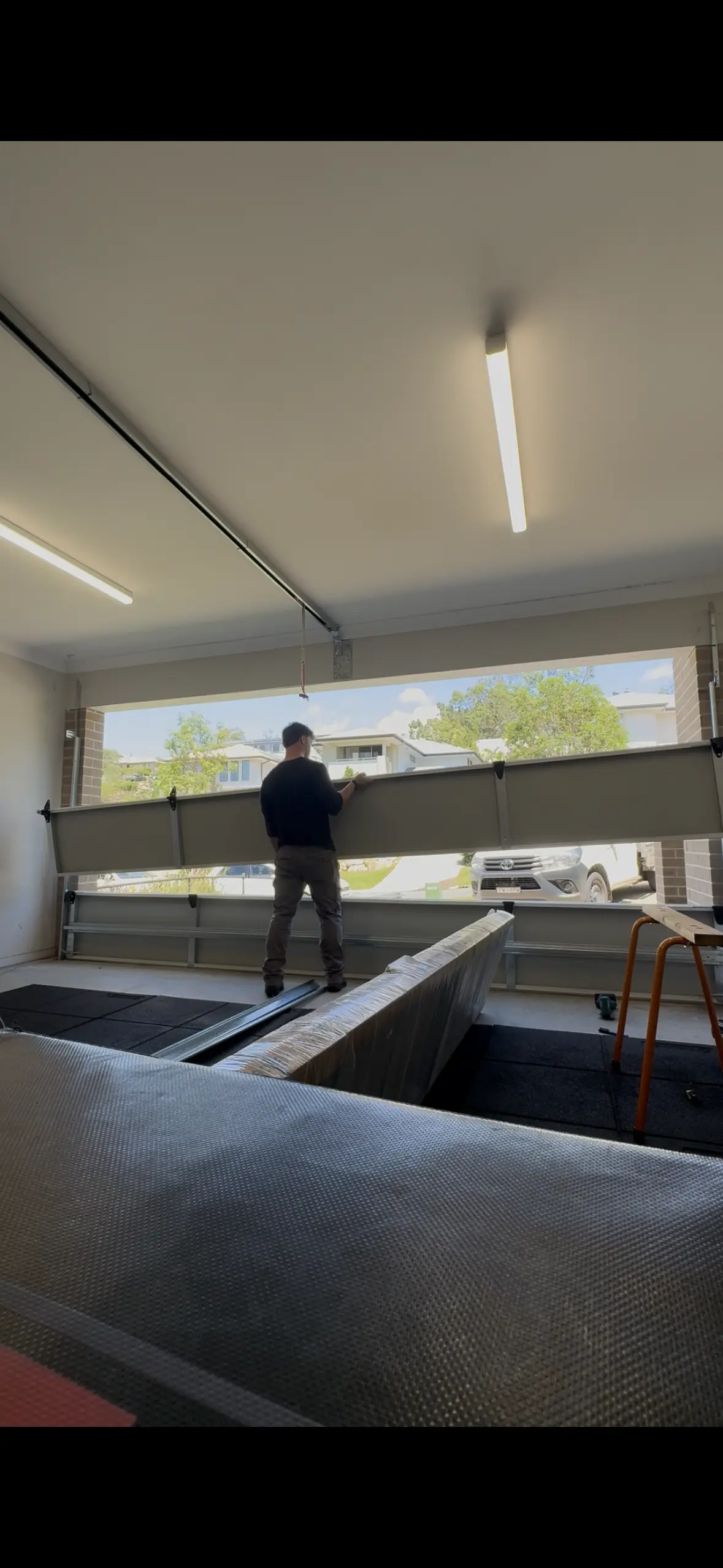 Professional garage door technician working on a sectional door installation inside a residential garage