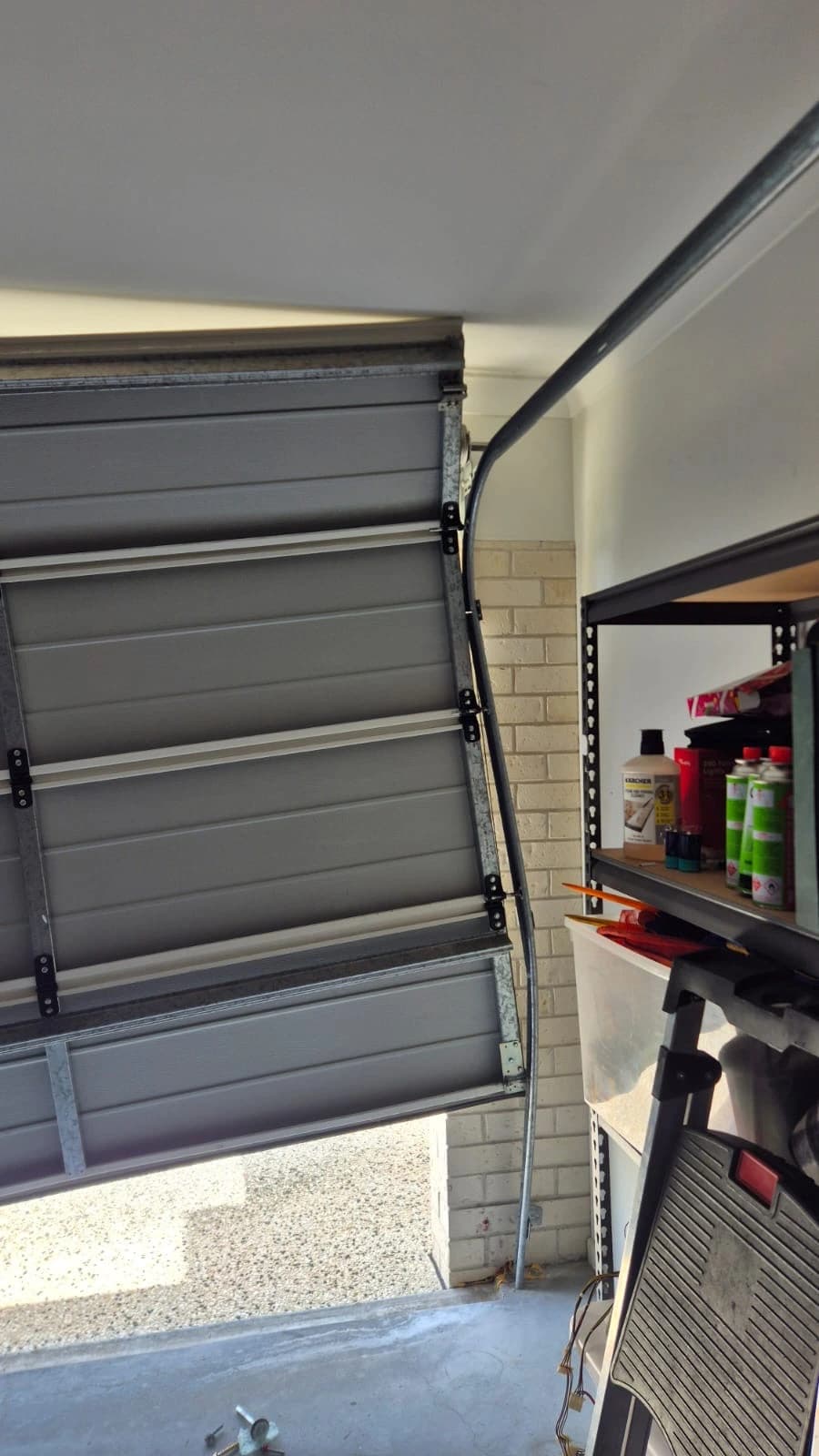 Off-track sectional garage door inside a residential garage before emergency repair