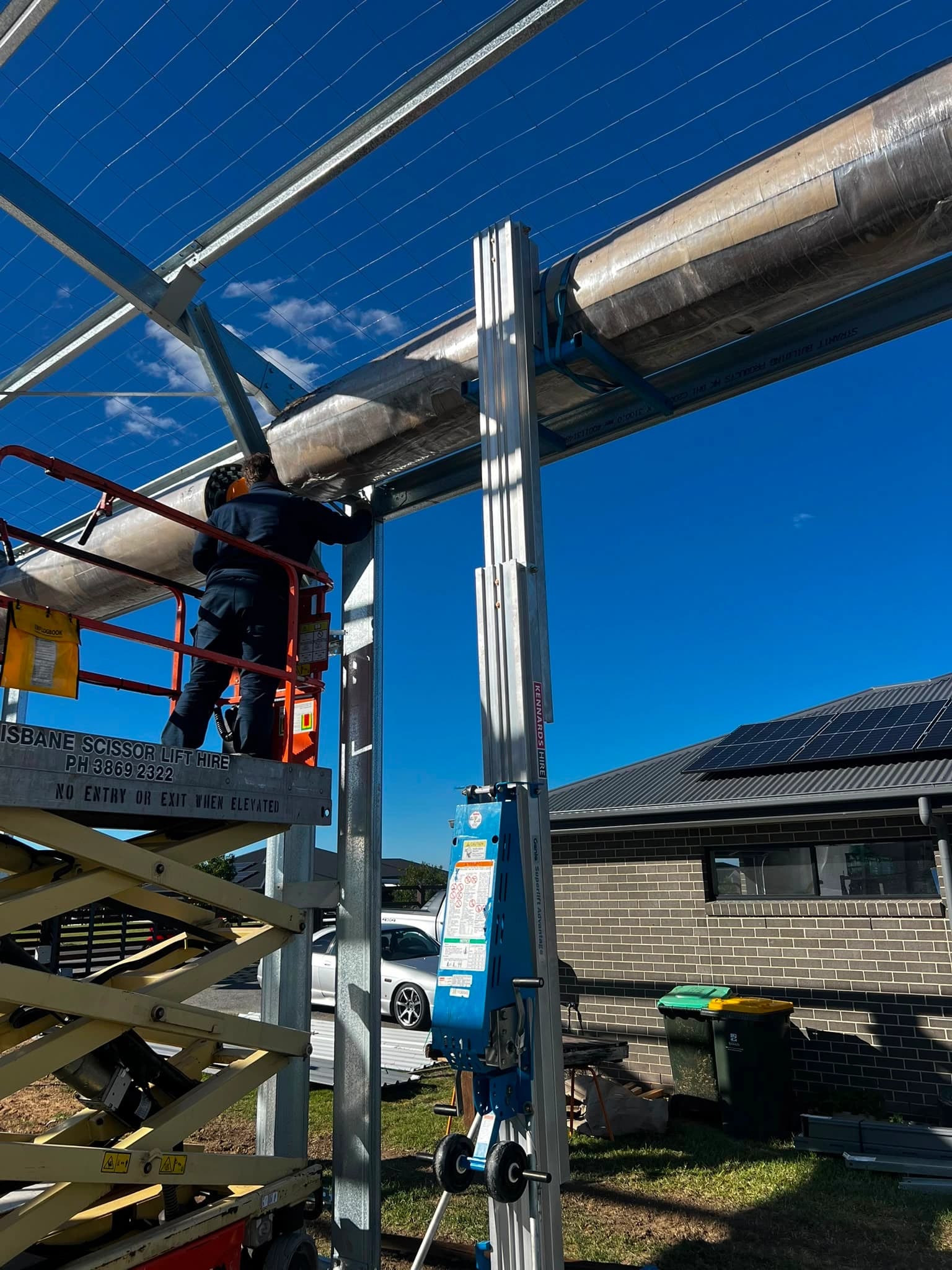 Technician installing a roller garage door frame from a scissor lift