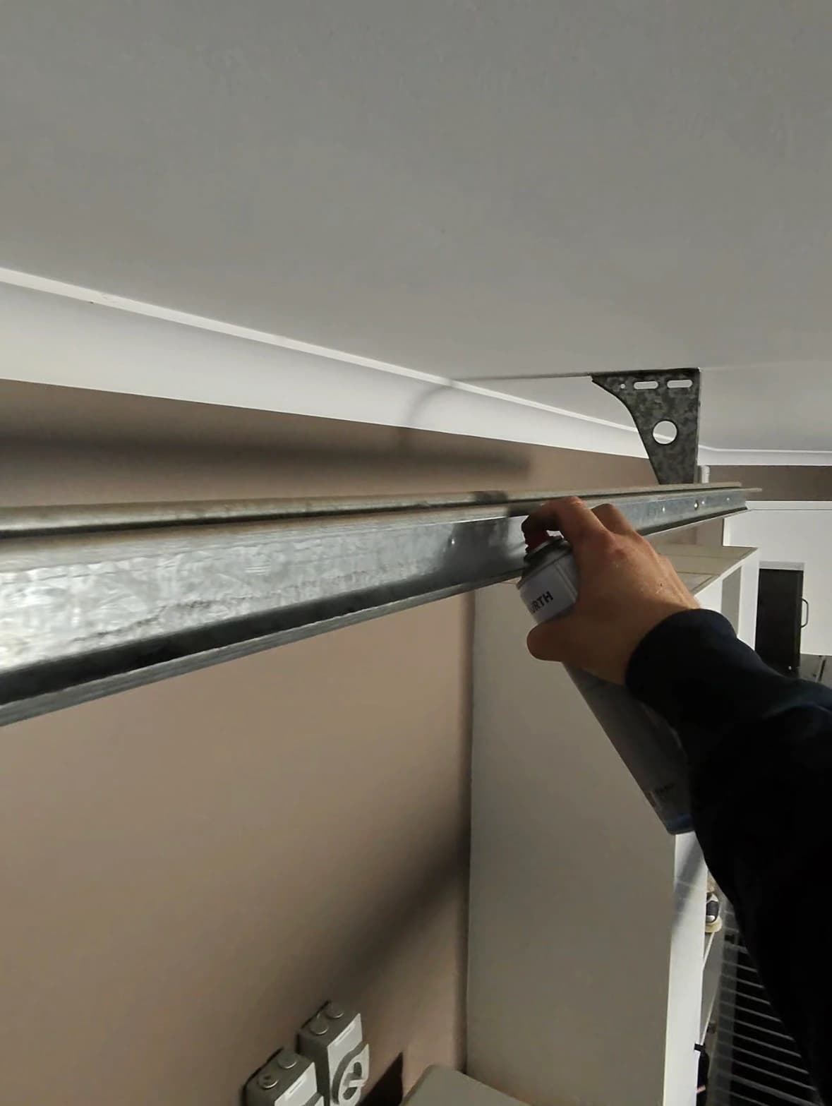 Technician applying lubricant to a residential garage door track during maintenance